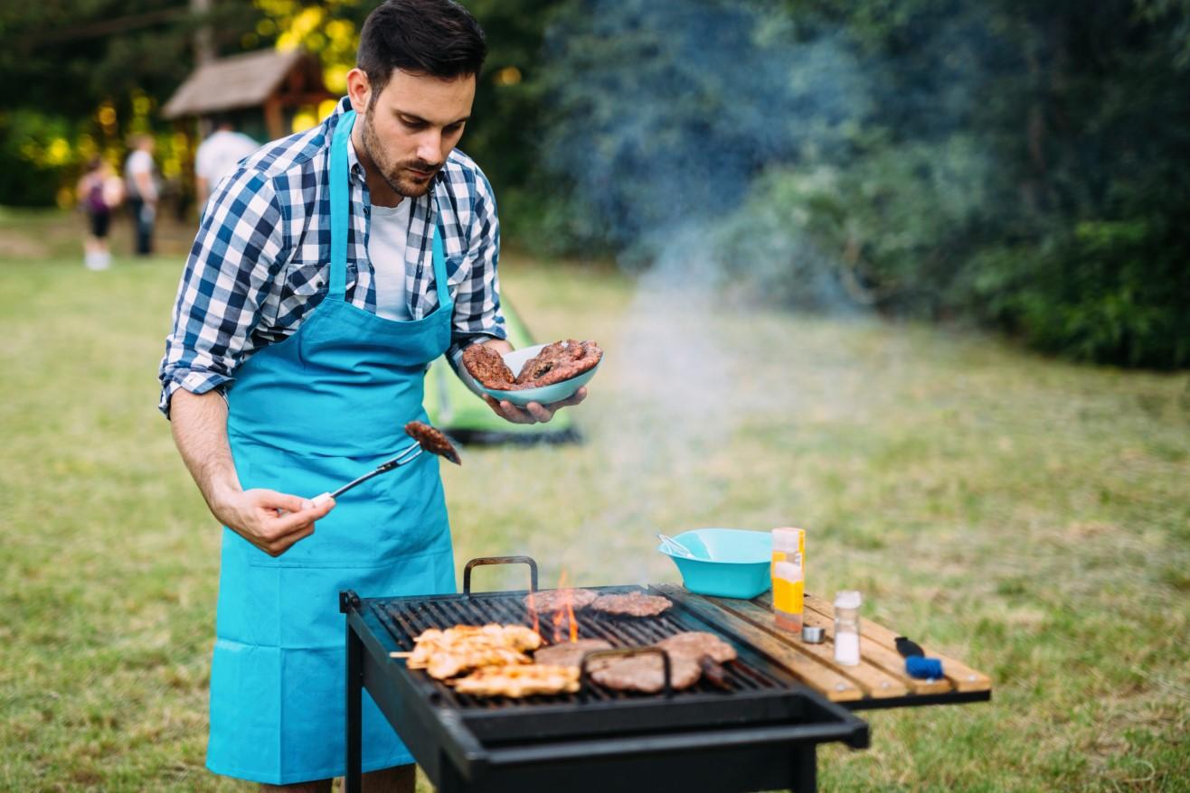 Happy male grilling bbq meat outdoor in nature